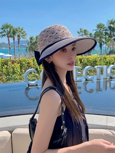 Detail of hollow straw sun hat featuring a chic black bow and beach resort style