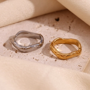Close-up of gold and silver hammered wave rings on beige stone and soft fabric