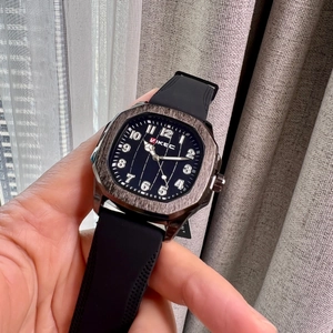 Men's square silver watch with black silicone strap and numeric dial on wrist