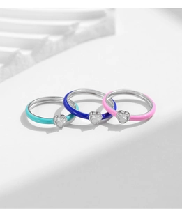 Detailed view of three colorful enamel heart rings with sparkling inlaid gemstones