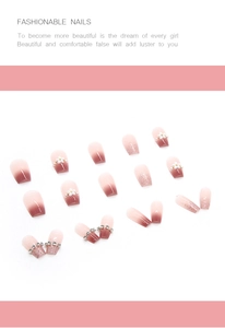 Macro detail of pink gradient press-on nails with 3D white flowers and silver rhinestones