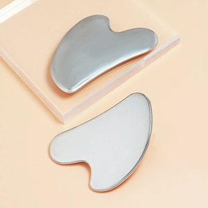 Detailed view of heart and triangle shaped stainless steel Gua Sha tools on acrylic stands