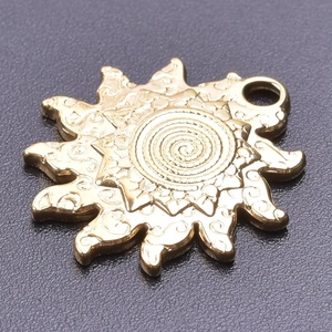 Detailed close-up of a 18k gold sun pendant with vintage spiral relief and floral pattern