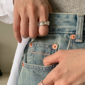 Close-up of 925 sterling silver bow ring worn on finger in a stylish lifestyle setting