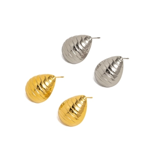 Detailed view of teardrop stud earrings in gold and silver with textured metal finish