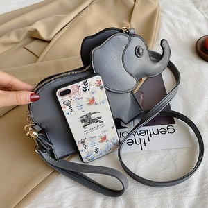 Deep grey elephant shaped crossbody bag with gold chain strap on a trench coat background
