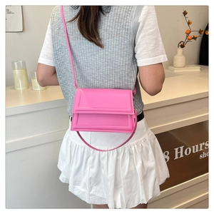 Detail of rose pink square crossbody bag with textured leather and geometric flap design