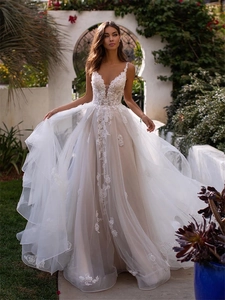 Exquisite close-up of intricate lace embroidery and deep V-neckline on a white bridal gown
