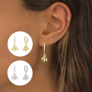 Close-up of gold and silver bee charm hoop earrings with crystal pavé and model view