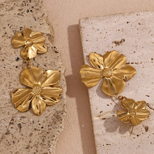 Detail of gold floral drop earrings with double flower charms on natural stone display