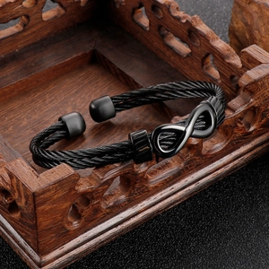Black infinity braided steel wire rope bracelet displayed on a vintage carved wooden box