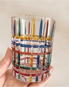 Close-up of hand holding a colorful hand-painted woven pattern crystal whiskey glass