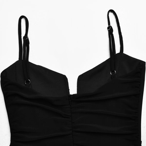 Detail of black V-neck dress featuring pleated texture and adjustable thin straps