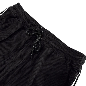 Close-up of black corduroy sweatpants featuring drawstring waist and white side stripes