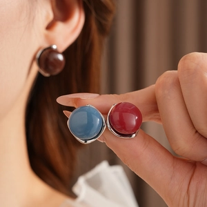 Dettaglio di orecchini geometrici in argento con pietre preziose blu e rosse tonde