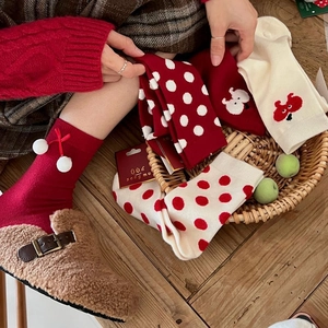 Thick red Christmas socks with cute cartoon patterns and festive bow in a gift basket