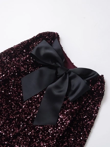 Macro shot of wine red sequins and a large black grosgrain bow on a fashion dress