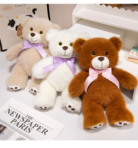 Three plush teddy bears with polka dot bowties in cream, white, and dark brown colors