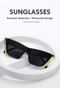 Close-up of black cat-eye sunglasses with gold metal trim and UV lenses on white