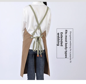 Detail of cross-back straps with metallic eyelets and leather reinforcement on canvas apron