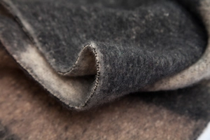 Macro detail of thick geometric knit scarf showing dark grey texture and stitching
