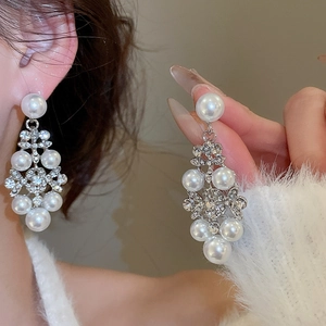 Détail de boucles d'oreilles argentées ornées de perles et de strass brillants