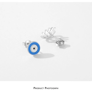 Gros plan sur les boucles d'oreilles asymétriques en argent S925 avec œil bleu émaillé