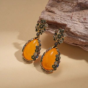 Boucles d'oreilles vintage avec résine orange et strass multicolores sur fond beige
