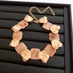 Detailed view of french style necklace with gold shell accents and beige resin squares