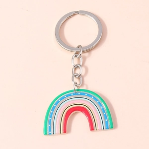 Close-up of rainbow keychain with colorful enamel stripes on a soft pink background