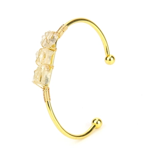 Macro shot of three natural raw citrine stones hand-wrapped on a gold open cuff bracelet