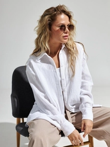 Close-up of white long-sleeved cotton crepe shirt showing natural texture and button detail