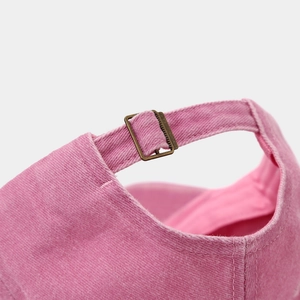 Detailed close-up of pink washed cotton baseball cap with adjustable metal buckle closure