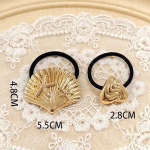Detail of golden metal scallop with sea stars and heart hair ring on lace background