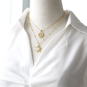Double-layered gold necklace featuring a Virgin Mary medal and colorful heart pendant