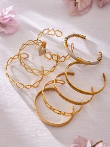 Detailed view of vintage gold hollow bangles with cream enamel on a white surface