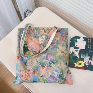 Detail of floral canvas tote bag showing bright oil painting flower patterns and cloth label