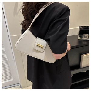 Minimalist beige baguette bag with vintage gold buckle shown as an underarm shoulder bag
