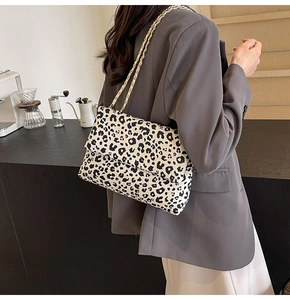 Détail d'un sac à bandoulière léopard stylé avec chaîne dorée dans un décor de café
