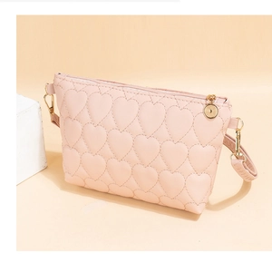 Close-up of pink faux leather bag with quilted heart pattern and metallic zipper detail