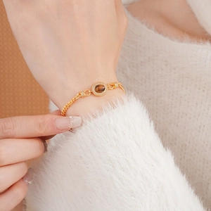 Gold-plated chain bracelet featuring an oval tiger eye stone with sparkling zircon border