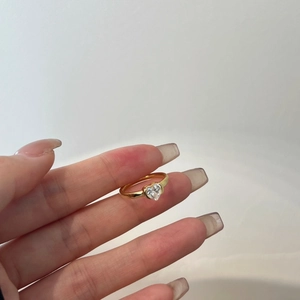 Close-up of a heart-shaped zircon gold ring worn on a finger showing elegant jewelry design