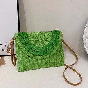 Detailed texture of emerald green raffia woven clutch bag with stylish layered fringes