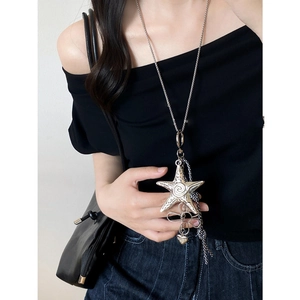 Close-up of a large silver starfish pendant with fine chain tassels on a long necklace