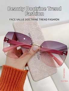 Detail of rimless sunglasses with purple gradient lenses and pink temples on a marble case