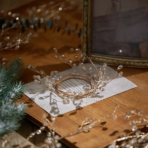 Elegant gold crystal crown with clear beads on a festive wooden Christmas background