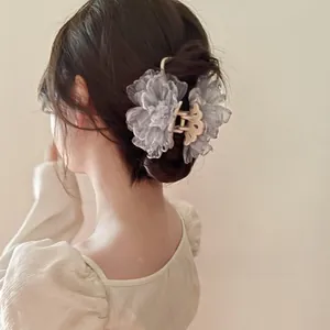 Rückansicht einer rauchgrauen Haarklammer mit Netzblume im Haar einer Frau