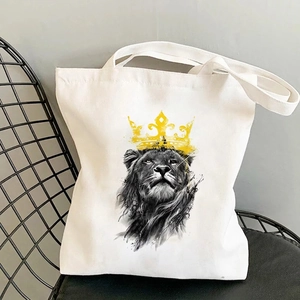 Weiße Canvas-Tasche mit Löwen-Print und gelber Krone auf einem schwarzen Metallstuhl