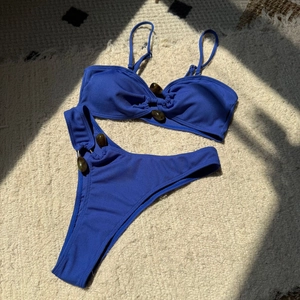 Close-up of ribbed navy blue bikini fabric with decorative dark stone beads on flat lay
