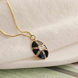 Détail macro du pendentif ovale en émail noir avec pierres multicolores et chaîne dorée